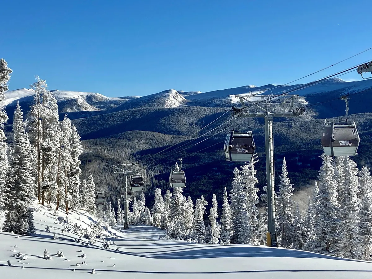 This image showcases ski lift gondolas gliding over snow-covered trees with a dramatic mountain backdrop. The pristine slopes are visible, reinforcing the winter adventure atmosphere. The scene is tranquil yet filled with the promise of excitement—a perfect visual for ski-in/ski-out access.