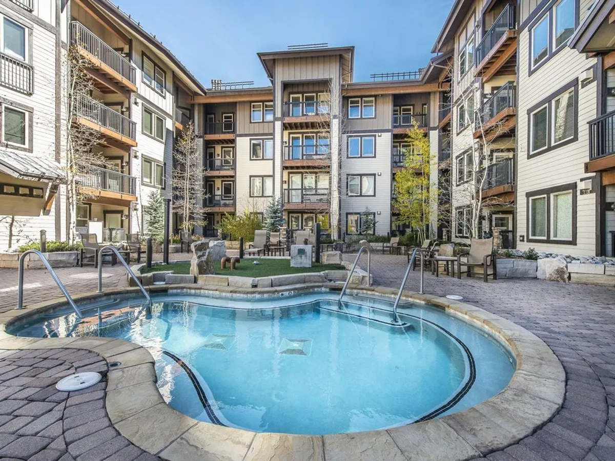 An inviting outdoor swimming pool surrounded by comfortable seating and abundant greenery, with the resort architecture providing a stylish backdrop. The atmosphere is lively yet relaxed, ideal for socializing or unwinding under the sun or stars.